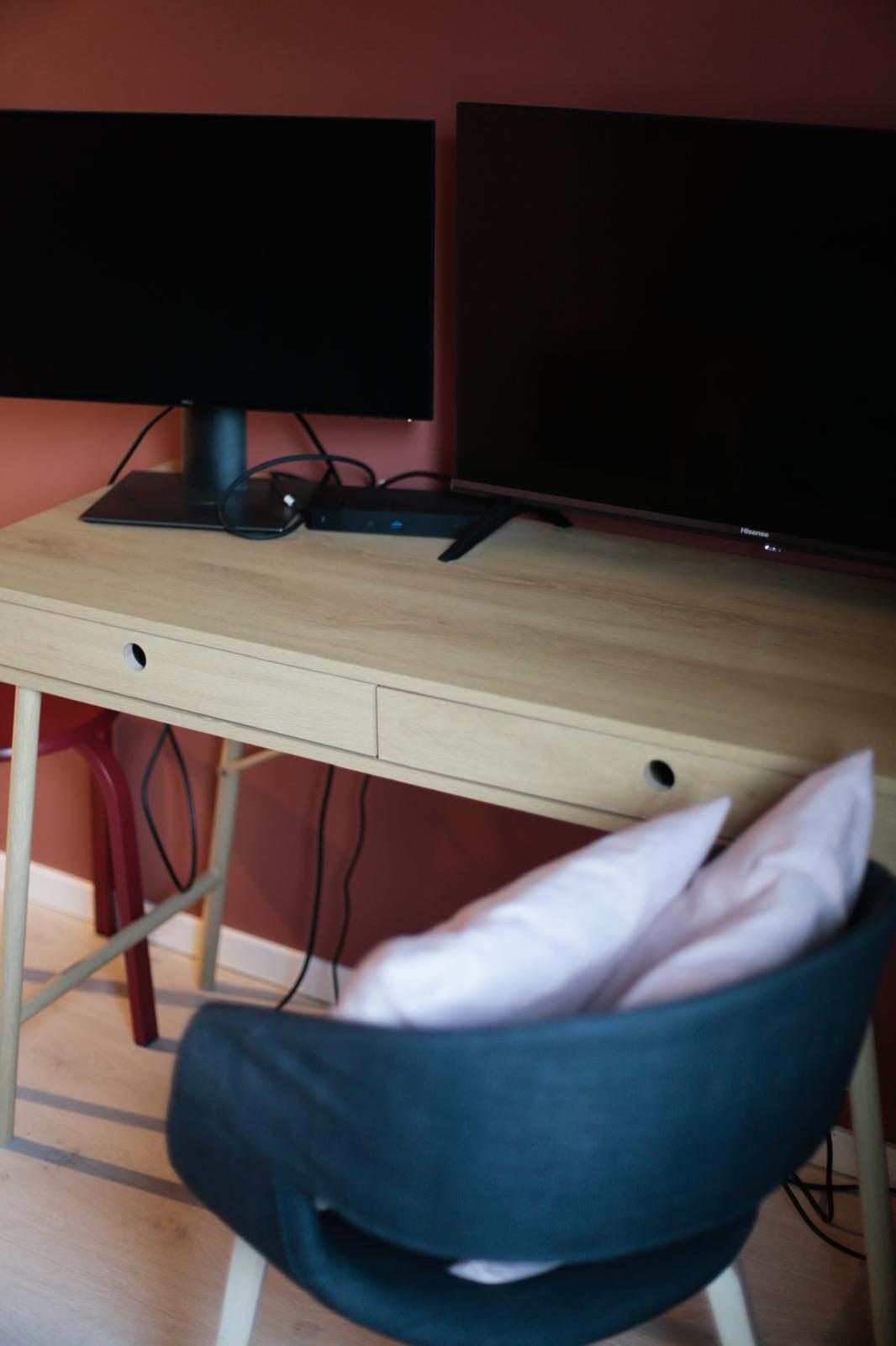 Suite 5 med skrivebord, skjerm og TV foran en terrakottafarget vegg